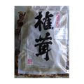 A clear plastic bag containing dried Chinese ginkgo biloba leaves, with a white paper label featuring large black Chinese characters and red seal stamps.