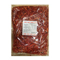 A clear plastic bag filled with sliced red chili peppers, with a white product label in the center, photographed against a plain white background.