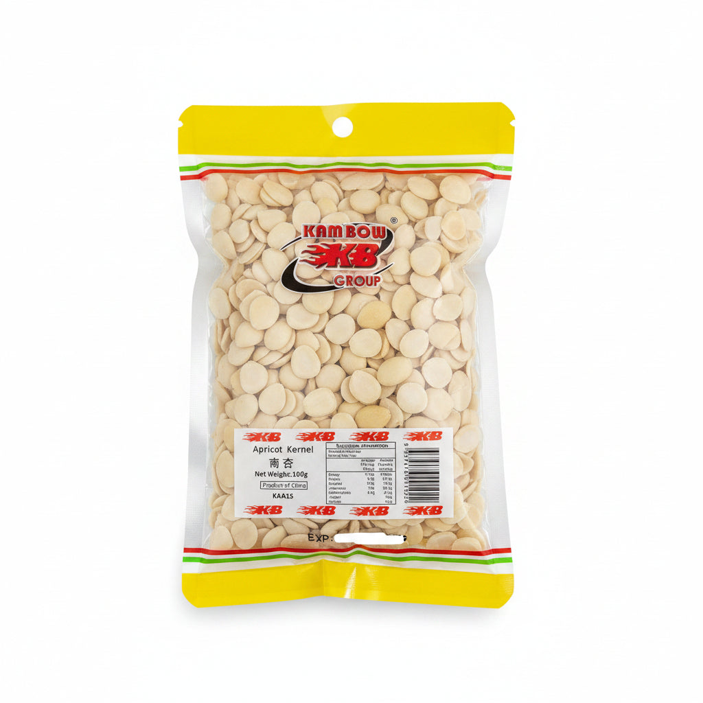 A clear plastic bag of Kam Bow Group Apricot Kernel snacks, showing the light beige apricot kernels inside, with a yellow and green branded header and a white product label at the bottom.